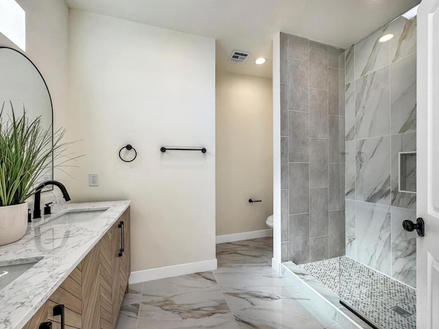 bathroom with a tile shower, vanity, and toilet