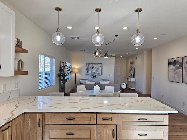 kitchen with pendant lighting, light brown cabinets, dark hardwood / wood-style floors, and light stone counters