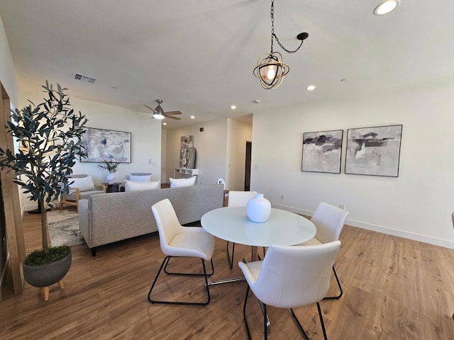 dining area featuring wood-type flooring and ceiling fan with notable chandelier