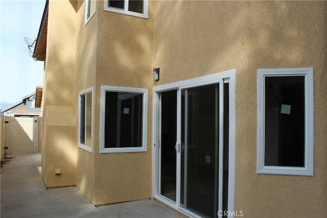 view of side of property featuring a patio, fence, and stucco siding