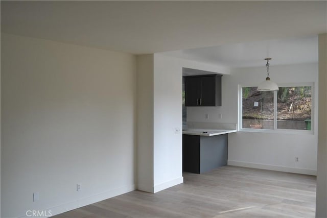 interior space featuring light wood-type flooring, baseboards, light countertops, and dark cabinetry