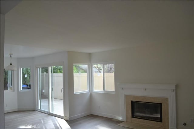 unfurnished living room with a fireplace with flush hearth, light wood-style flooring, and baseboards