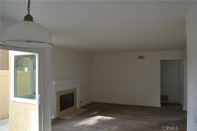 unfurnished living room with a fireplace with flush hearth, dark wood-style flooring, and visible vents