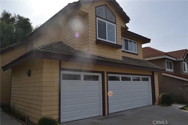 view of home's exterior with an attached garage, concrete driveway, and a tiled roof