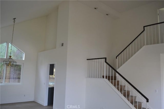 stairway featuring visible vents, a high ceiling, an inviting chandelier, wood finished floors, and baseboards