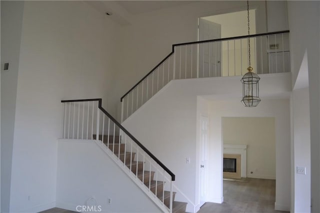 staircase featuring a high ceiling, baseboards, and a glass covered fireplace