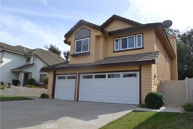 view of front of property featuring a garage, fence, and concrete driveway