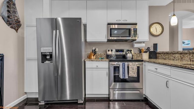 kitchen with pendant lighting, dark stone countertops, stainless steel appliances, dark hardwood / wood-style floors, and white cabinets