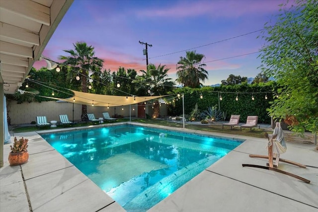 pool at dusk featuring a patio