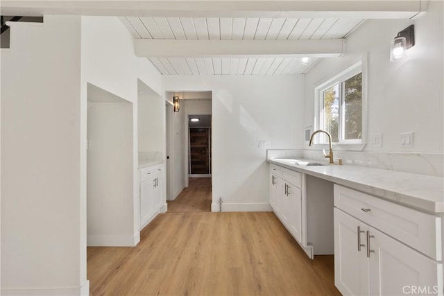 kitchen with white cabinets, sink, beamed ceiling, and light hardwood / wood-style flooring