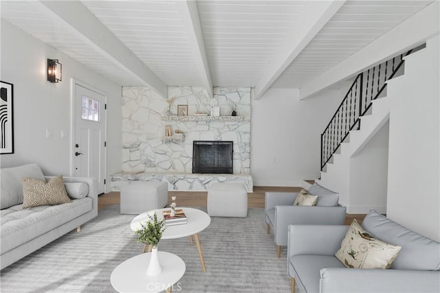 living room with beam ceiling and a stone fireplace