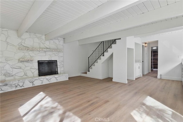 unfurnished living room with beamed ceiling, light hardwood / wood-style flooring, and a fireplace