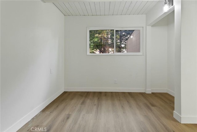 empty room featuring light wood-type flooring and wooden ceiling