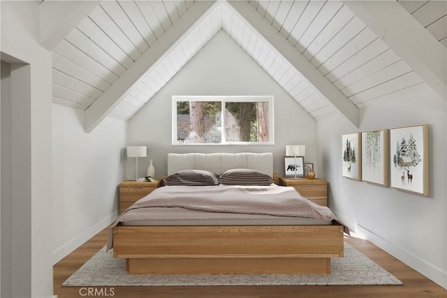 bedroom with lofted ceiling with beams and hardwood / wood-style flooring