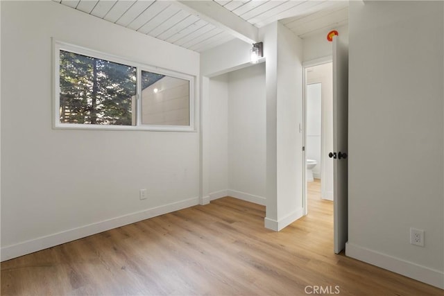 empty room featuring beam ceiling, wooden ceiling, and light wood-type flooring