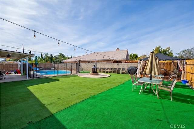 view of yard featuring a fenced in pool, an outdoor fire pit, and a patio area