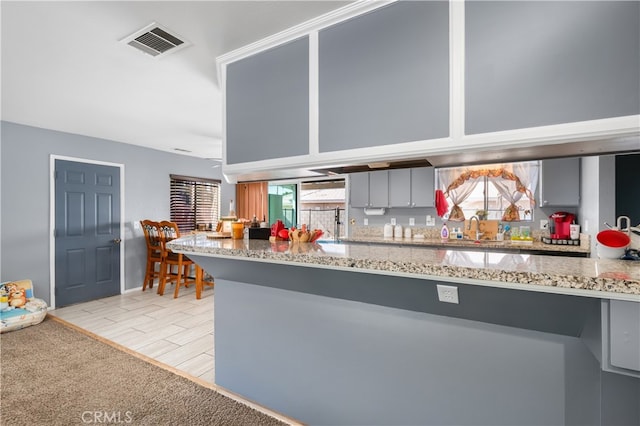 kitchen with gray cabinetry, a wealth of natural light, sink, and light hardwood / wood-style floors