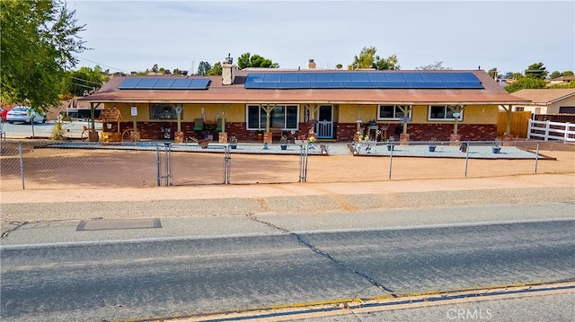 ranch-style home with a porch and solar panels