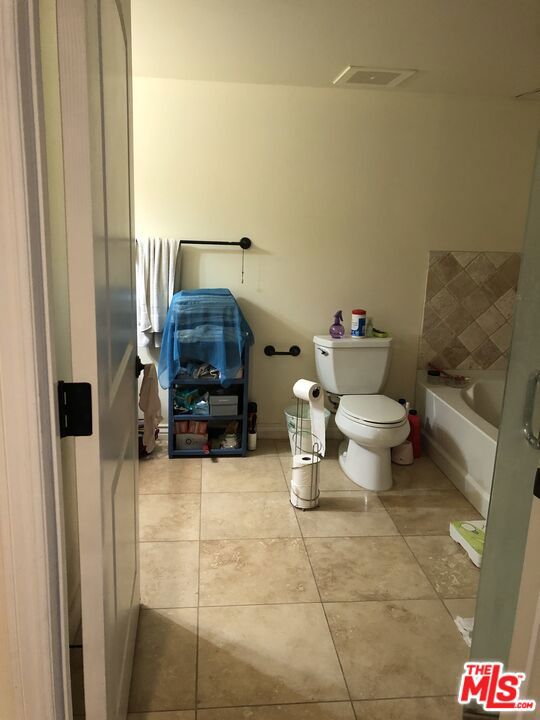 bathroom featuring tile patterned flooring, a tub to relax in, and toilet