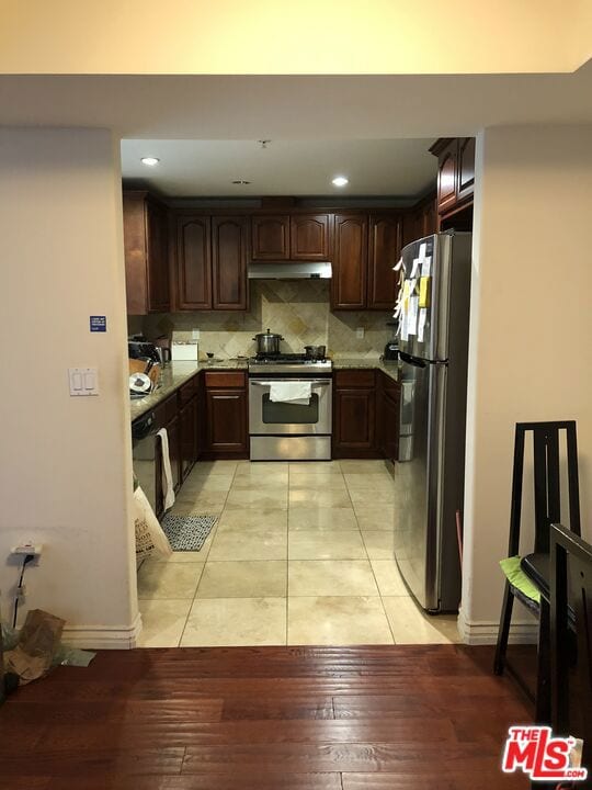 kitchen featuring decorative backsplash, dark brown cabinetry, light wood-type flooring, and stainless steel appliances