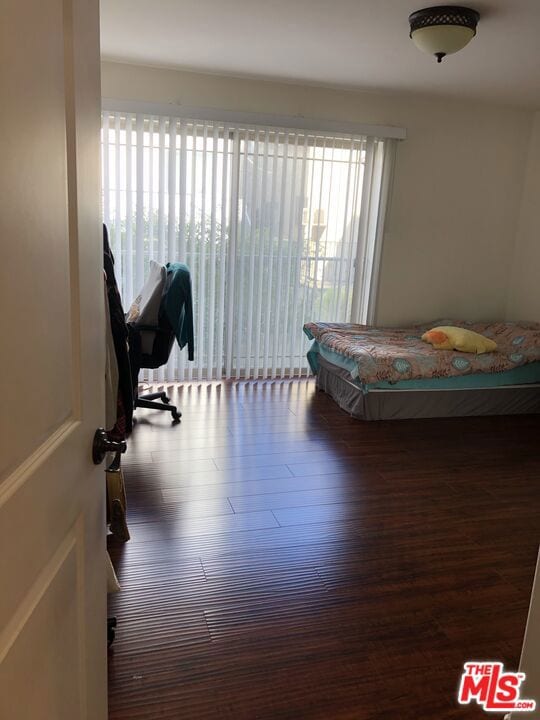 bedroom with multiple windows and dark hardwood / wood-style floors