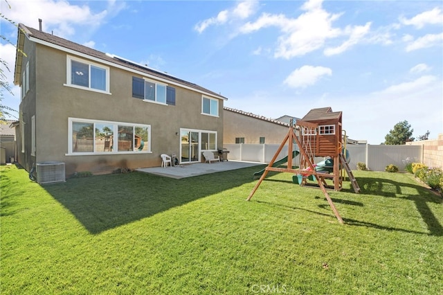 rear view of property featuring a playground, central AC unit, a lawn, and a patio