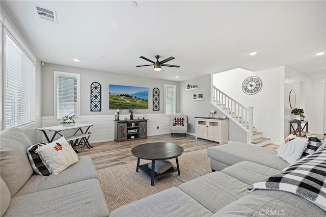 living room with light wood-type flooring, ceiling fan, and a healthy amount of sunlight