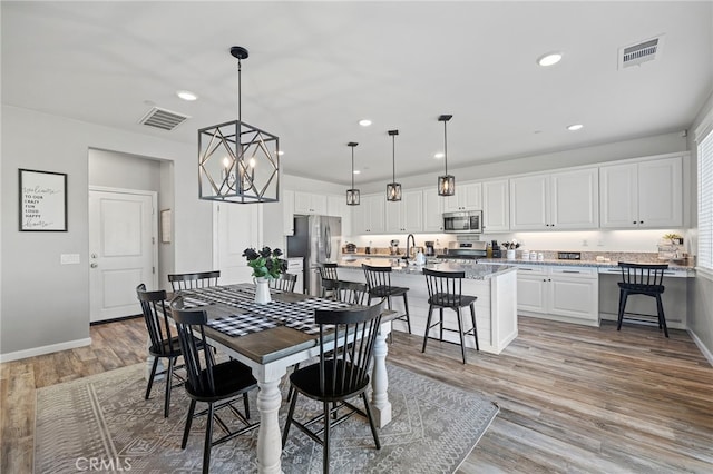 dining space with light wood-type flooring and a notable chandelier