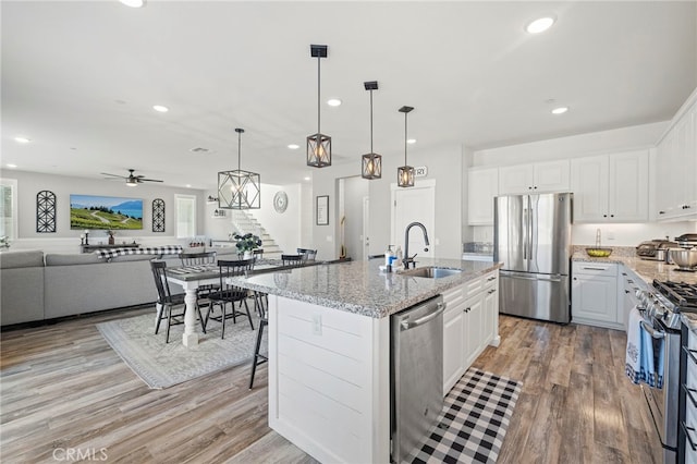 kitchen featuring sink, white cabinets, appliances with stainless steel finishes, and a center island with sink