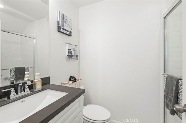 bathroom featuring toilet, vanity, and a shower with shower door