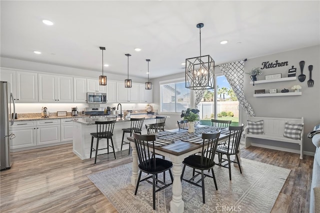 dining space featuring sink, an inviting chandelier, and hardwood / wood-style flooring