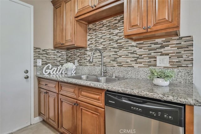 kitchen with decorative backsplash, stainless steel dishwasher, light stone countertops, and sink