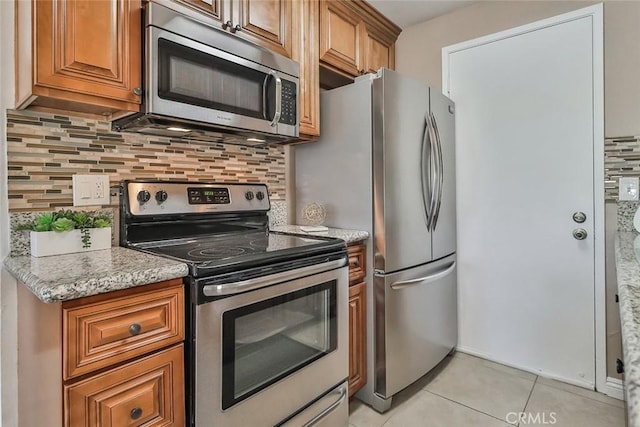 kitchen with decorative backsplash, light stone countertops, light tile patterned floors, and stainless steel appliances