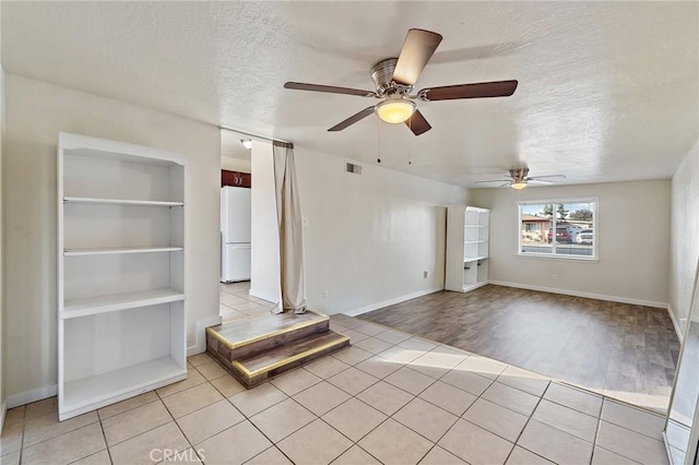 unfurnished living room featuring ceiling fan, light hardwood / wood-style floors, built in features, and a textured ceiling