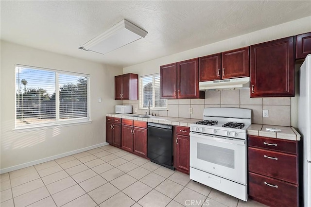 kitchen with light tile patterned floors, white appliances, backsplash, and a wealth of natural light