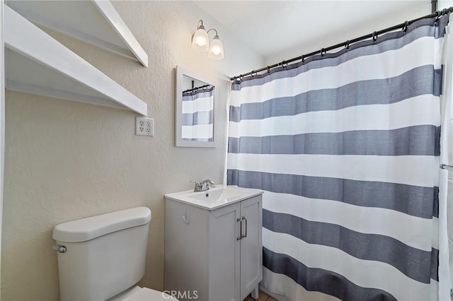 bathroom featuring vanity, toilet, and walk in shower