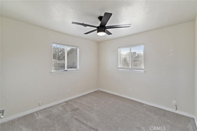 spare room with a textured ceiling, light colored carpet, and ceiling fan