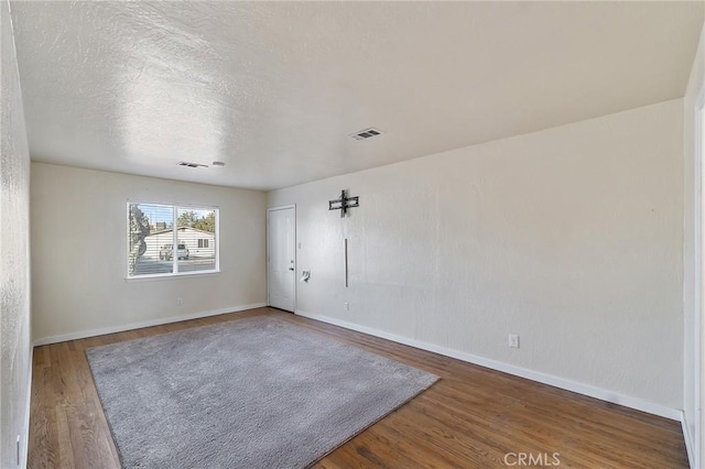 spare room featuring hardwood / wood-style floors and a textured ceiling