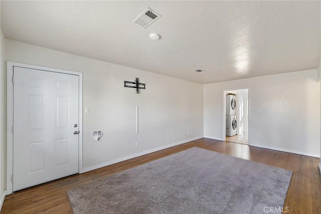 unfurnished room with dark hardwood / wood-style flooring and stacked washer / dryer