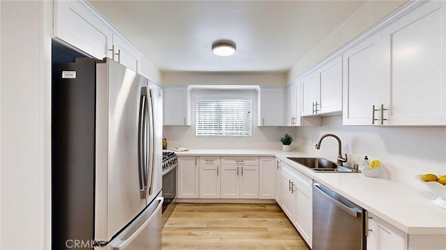 kitchen featuring sink, white cabinets, light hardwood / wood-style floors, and appliances with stainless steel finishes