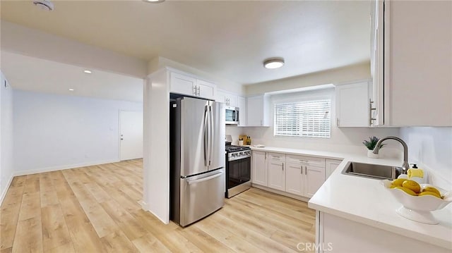 kitchen featuring white cabinets, appliances with stainless steel finishes, light hardwood / wood-style floors, and sink