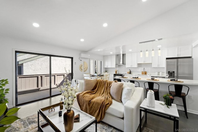 living room featuring a wall mounted air conditioner, light hardwood / wood-style floors, lofted ceiling, and sink