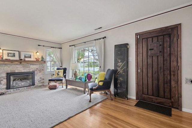 living area with a stone fireplace and light hardwood / wood-style floors