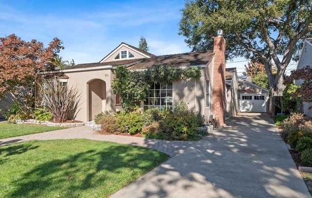 view of front of house with an outbuilding, a garage, and a front lawn