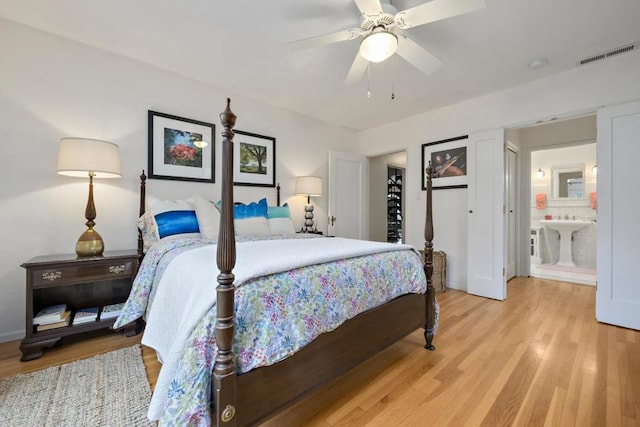 bedroom featuring ceiling fan, sink, light hardwood / wood-style floors, and ensuite bath