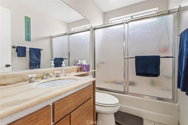 full bathroom featuring tile patterned floors, vanity, toilet, and shower / bath combination with glass door