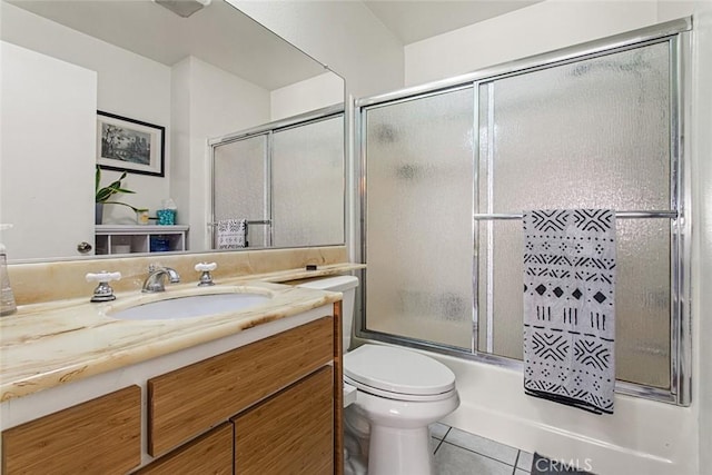 full bathroom with combined bath / shower with glass door, vanity, tile patterned floors, and toilet