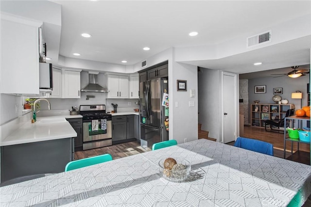 kitchen with wall chimney exhaust hood, sink, appliances with stainless steel finishes, gray cabinets, and light hardwood / wood-style floors