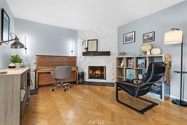 home office featuring light parquet flooring and a stone fireplace