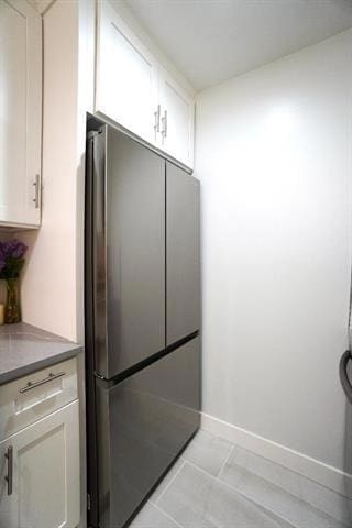 kitchen featuring white cabinets, stainless steel fridge, and light tile patterned floors